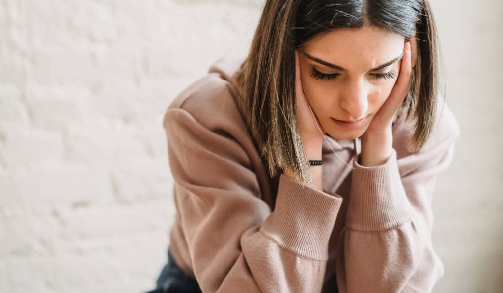 A woman is placing her hands on her ears while being faced down in sadness.