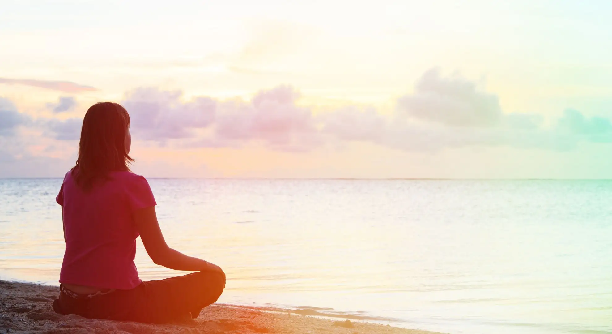 person meditating against a rising sun