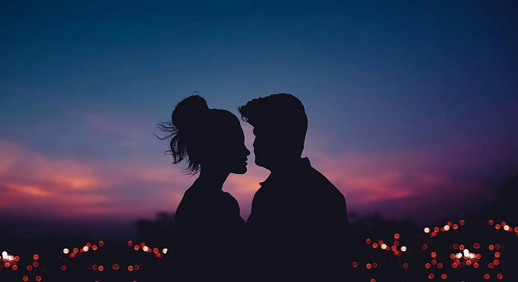 a couple about to kiss against pink purple evening sky