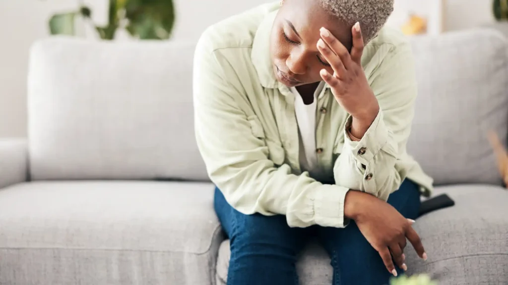 a person sitting on a couch with their head in their hands