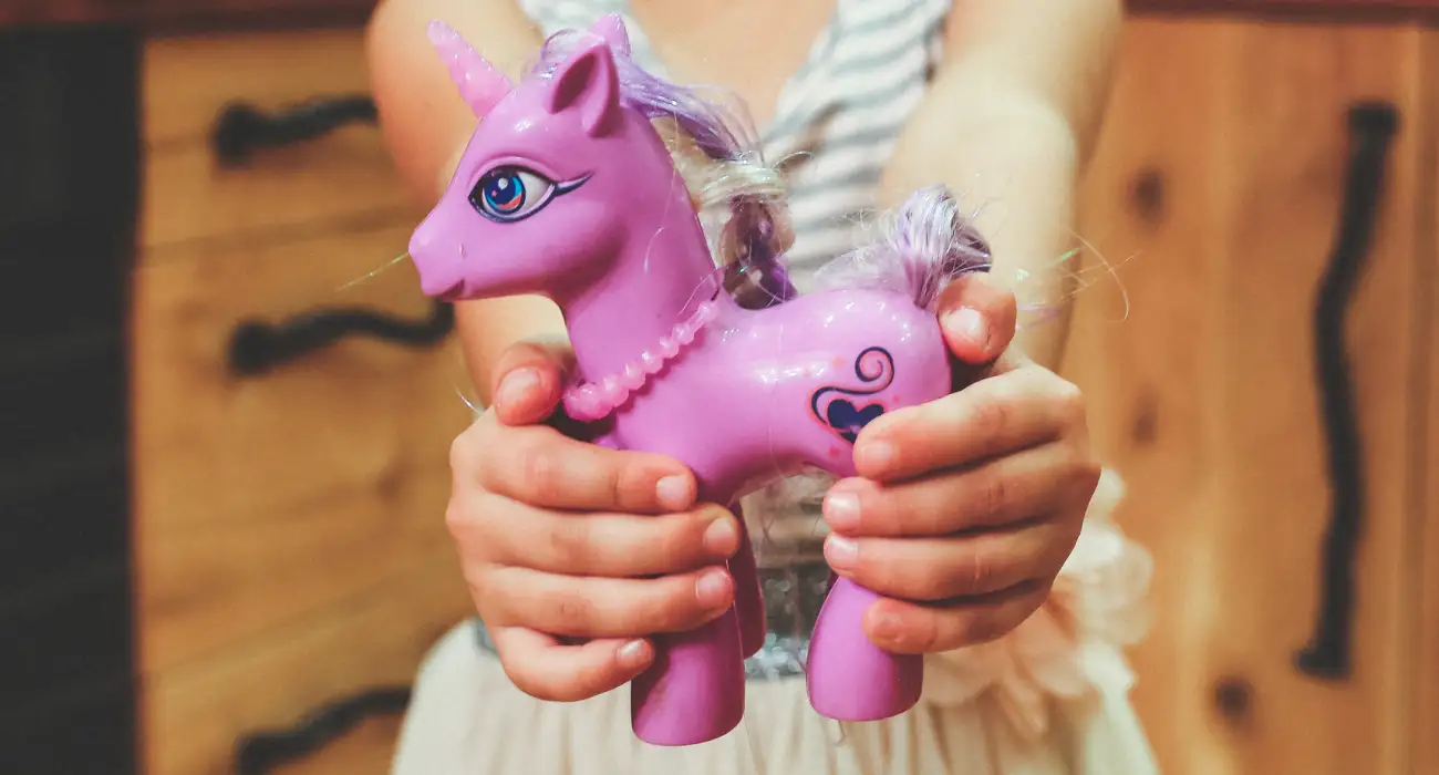 child playing with a pink pony demonstrating play therapy