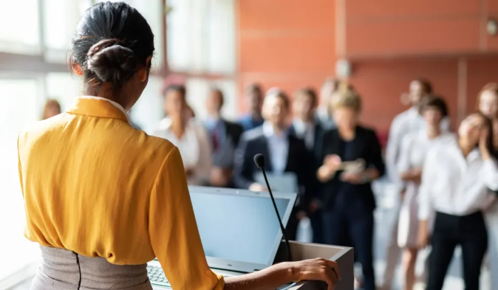 A person speaking in front of a crowd.