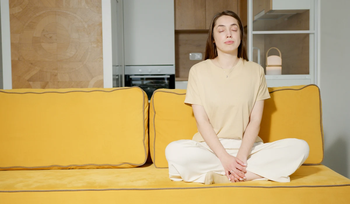 woman sitting calmly with her eyes closed on a couch